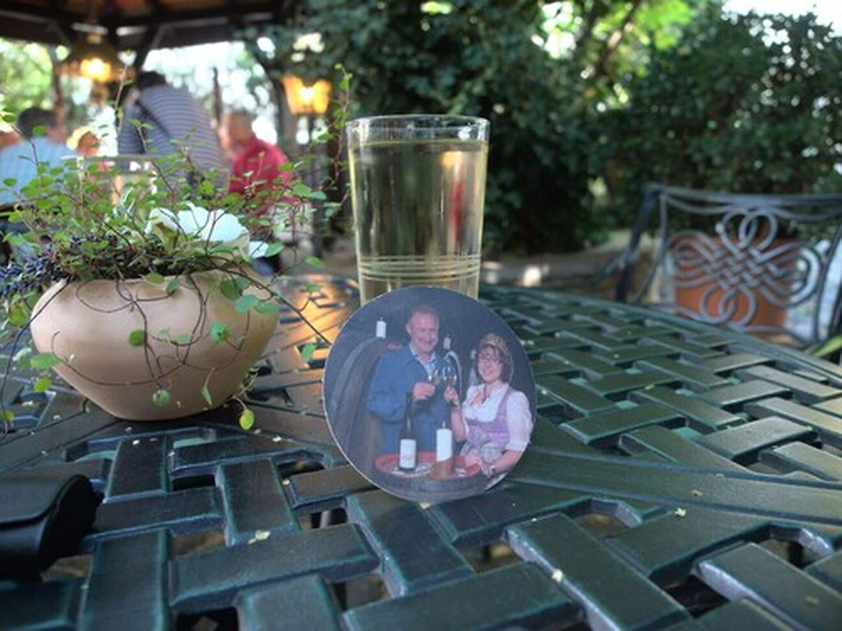 A table with a potted plant, a glass of water, and a photo frame.