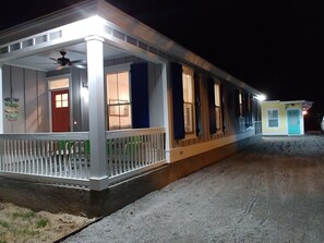 A two-story building with a porch, a red door, and multiple windows.