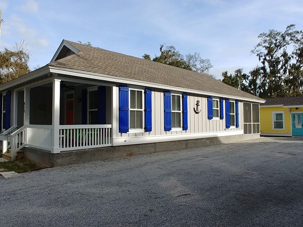 A single-story building with a porch, blue shutters, and a small anchor decoration.