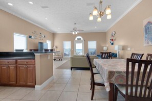 A spacious kitchen with a central island, a dining area with a table and chairs, and a ceiling fan.