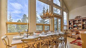 A dining area with a large table set for six, surrounded by wooden chairs, large windows, and a chandelier. - Ski-In/Out Breckenridge Gem w/ Hot Tub! (Breckenridge)