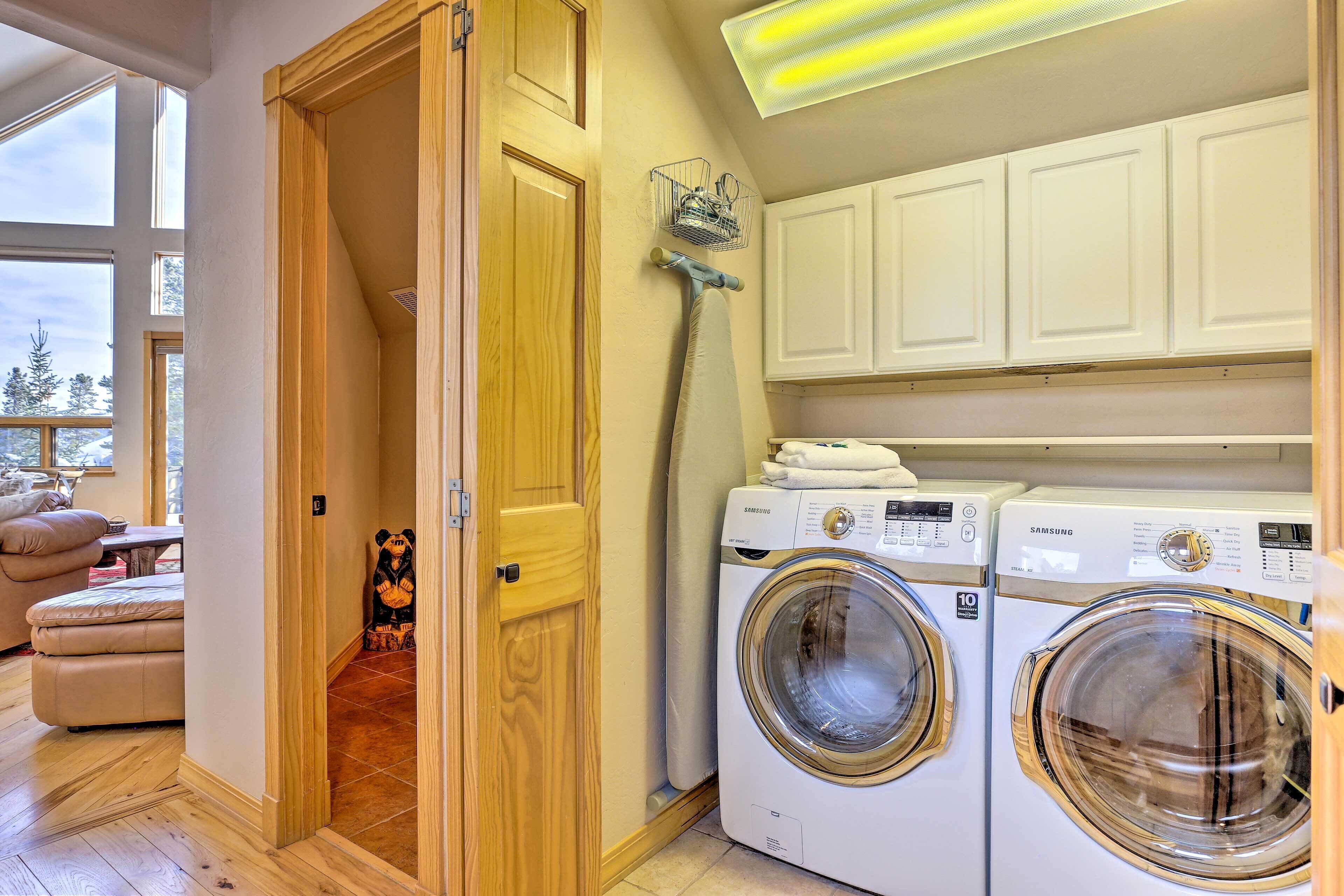 A laundry room with two Samsung washing machines, wooden cabinets, and a large window.