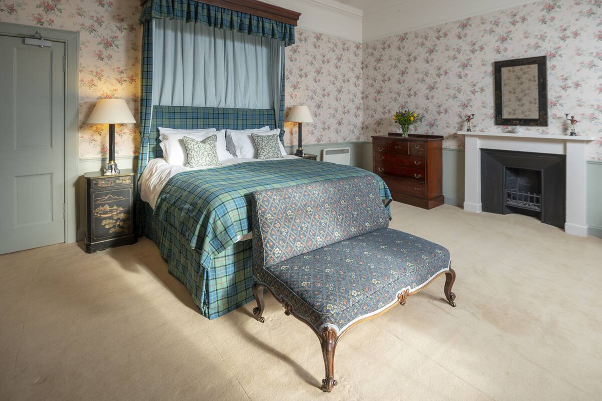 Un dormitorio con una cama grande, una mesita de noche, un aparador y un banco.