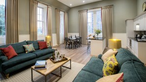 A spacious living room with a sofa, coffee table, and dining area. - Thirlestane Castle (Lauder)