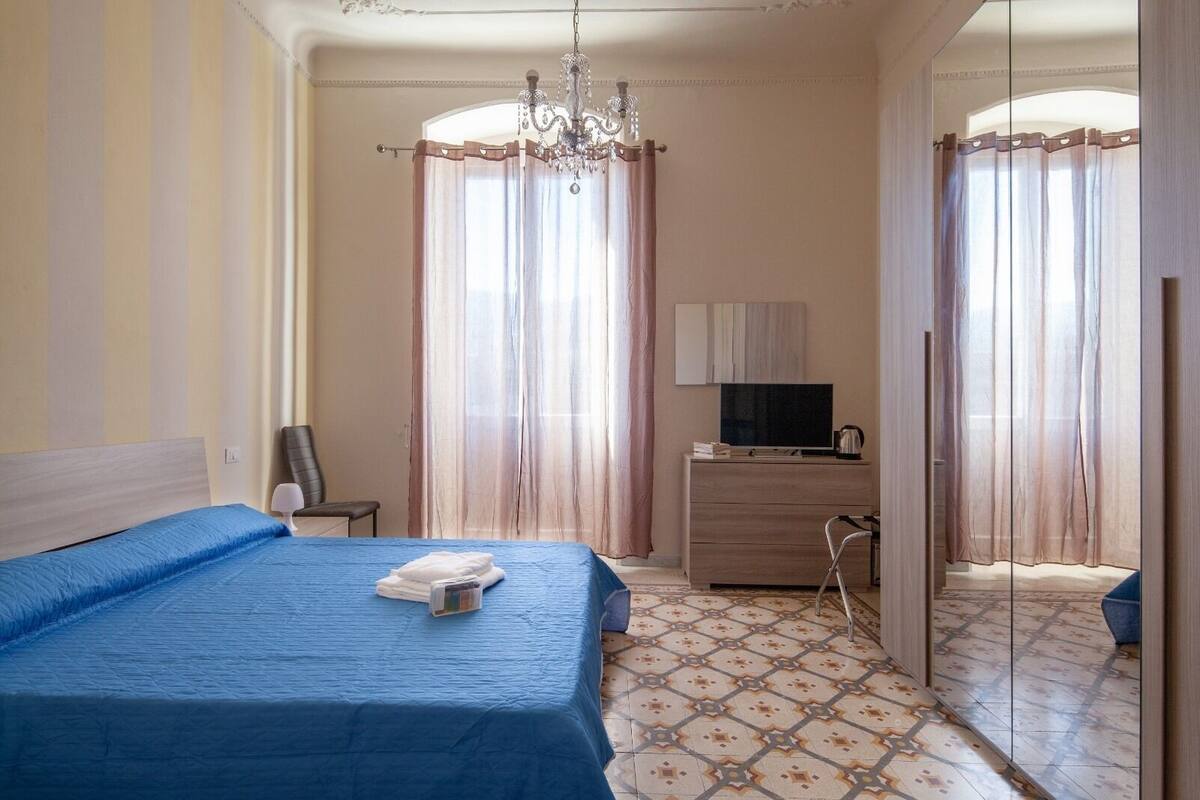Habitació d'hotel amb un llit gran, un taulell, una televisió i un mirall.