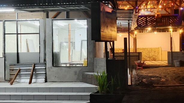 A building with a concrete facade, large windows, and a small porch area with steps leading up to the entrance. - Angin Mamiri Rinjani Cottages And Resto (Bayan)