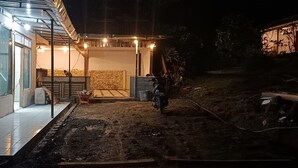 A building with a covered outdoor area, a motorcycle parked outside, and a paved path leading to the entrance. - Angin Mamiri Rinjani Cottages And Resto (Bayan)