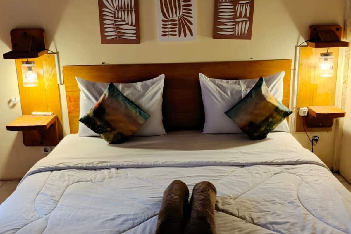 A bed with a wooden headboard, two wall-mounted lamps, and two decorative wall panels.