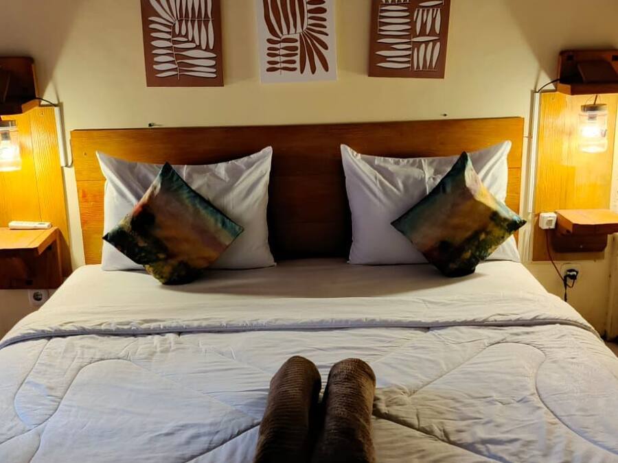 A bed with a wooden headboard, two wall-mounted lamps, and two decorative wall panels.