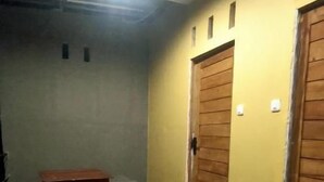 A room with a tiled floor, a small table, and two wooden doors. - Angin Mamiri Rinjani Cottages And Resto (Bayan)
