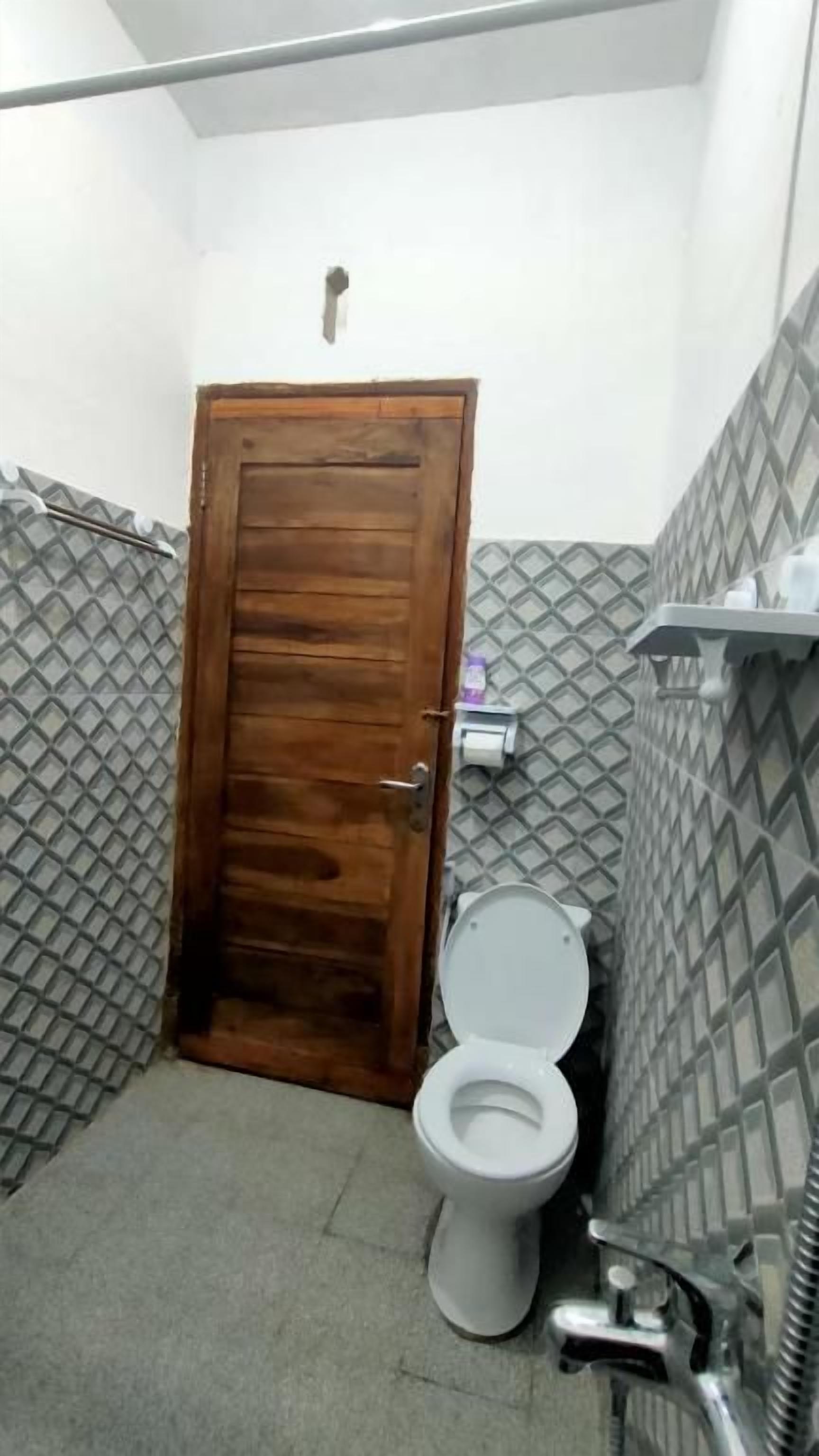 Un baño pequeño con puerta de madera, un inodoro y zona de ducha.
