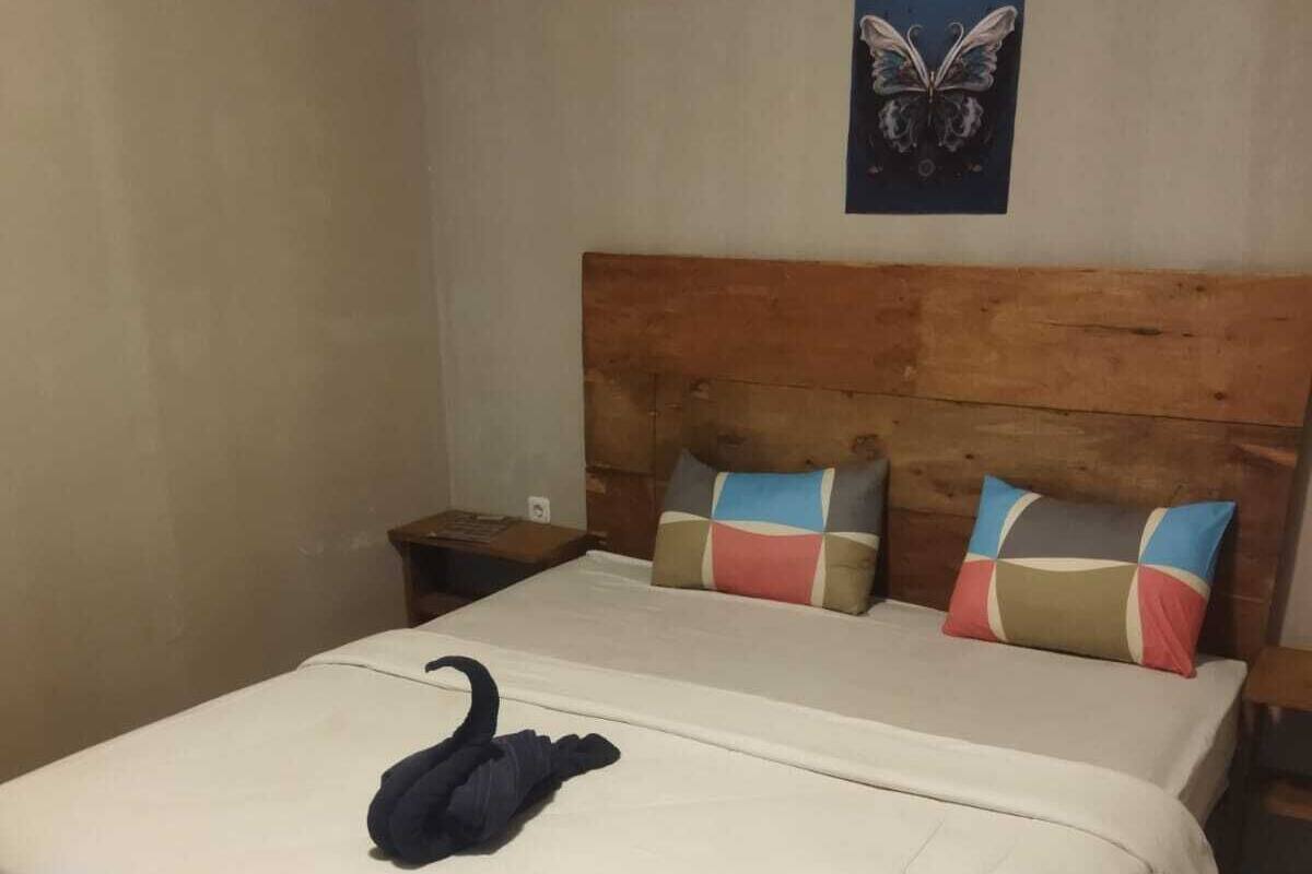 A bed with a wooden headboard, white bedding, and a swan-shaped pillow.