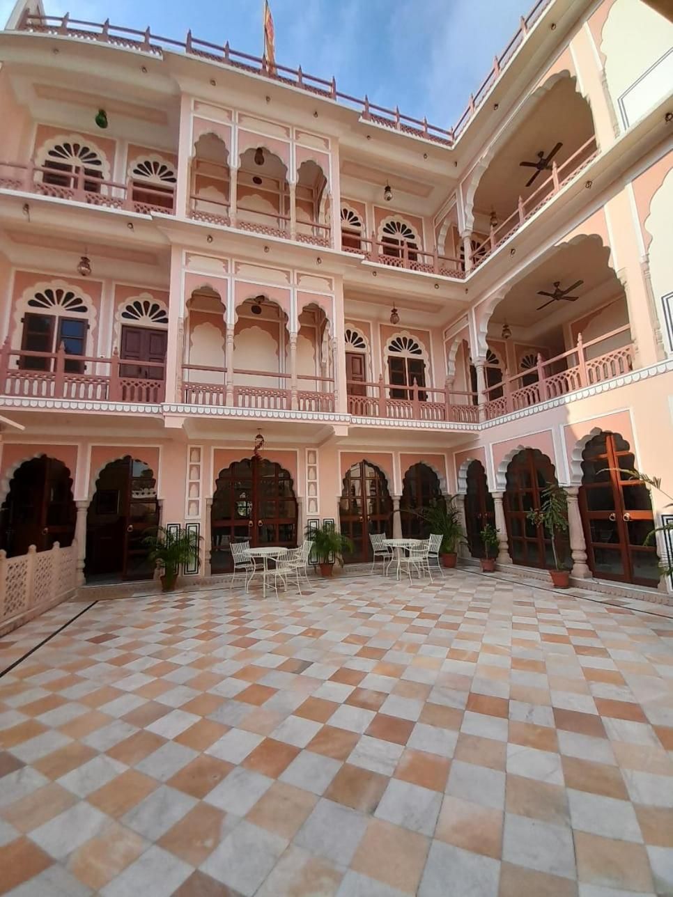 A courtyard with a checkered floor, multiple balconies, and potted plants.