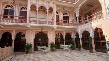 A courtyard with a checkered floor, multiple balconies, and potted plants.