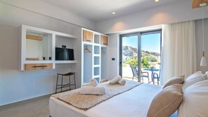 Een moderne hotelkamer met een groot bed, een televisie, een garderobe en een balkon met uitzicht op de heuvels.