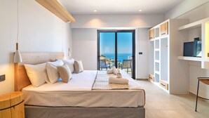 Een moderne slaapkamer met een groot bed, een televisie, inbouwkasten en een balkon met uitzicht op zee.