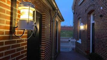A narrow brick alleyway with a wooden bench and a potted plant.
