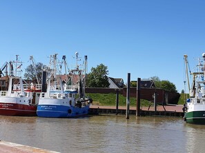 A marina with several boats docked, a clear sky, and a building with a red roof in the background.