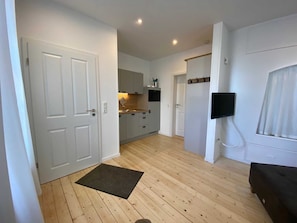 Une cuisine moderne avec des meubles blancs, un plancher en bois et un paillasson noir.