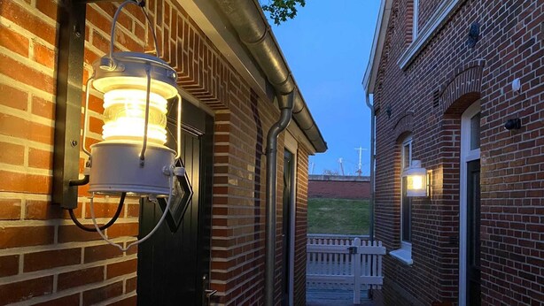 A narrow brick alleyway with a wooden bench and a potted plant. - Berth 6 - Apartments Meerhuus, 45229 (Jemgum)