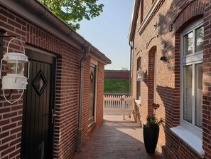A brick building with a gated entrance, a lantern, and a potted plant. - Berth 6 - Apartments Meerhuus, 45229 (Jemgum)
