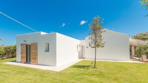 A modern white building with a small tree in the front yard.