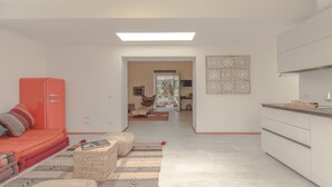 A modern living room with a sofa, a red refrigerator, and a patterned rug.