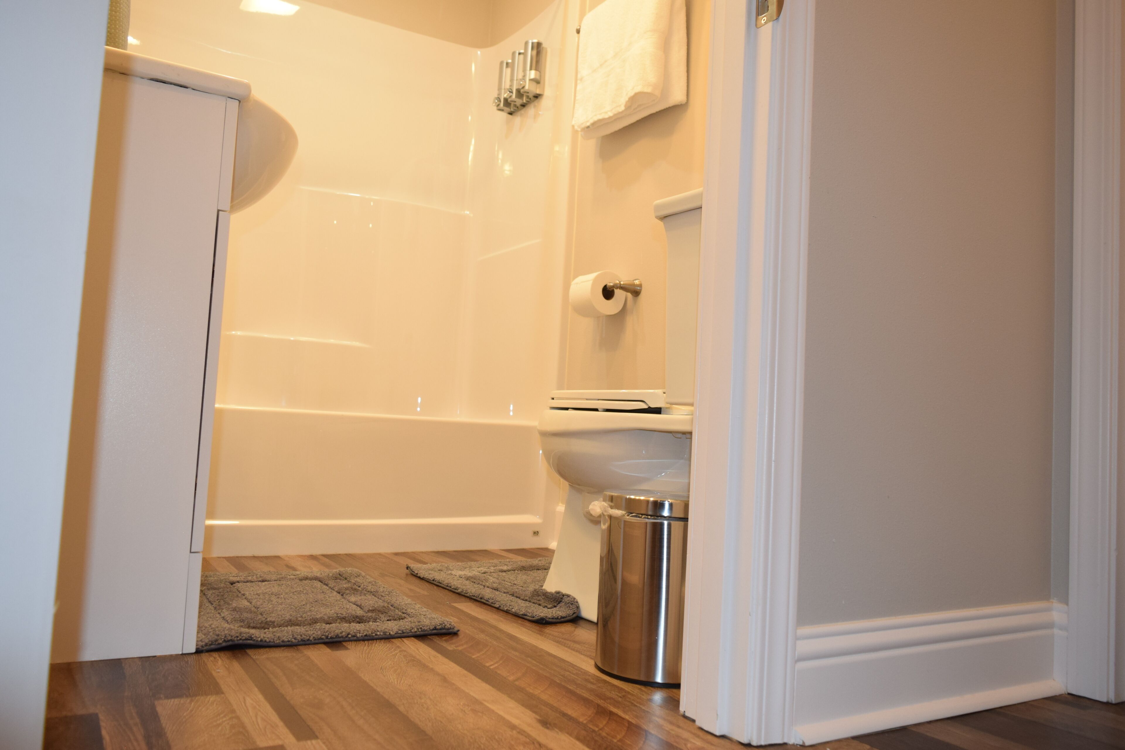 A bathroom with a toilet, a shower, and a trash can.