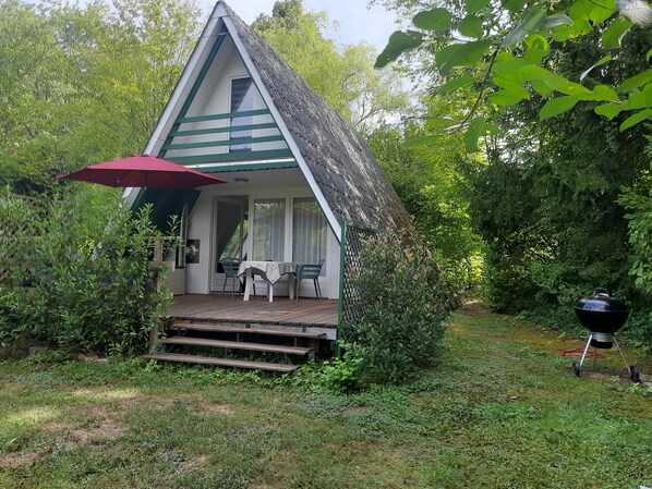 A small, triangular-shaped building with a porch and a table set for two. - Idyllic Holiday Home in the Palatinate Forest (Gossersweiler-Stein)