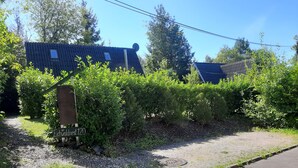Une propriété résidentielle avec une allée en gravier, un panneau en bois et un portail en métal.