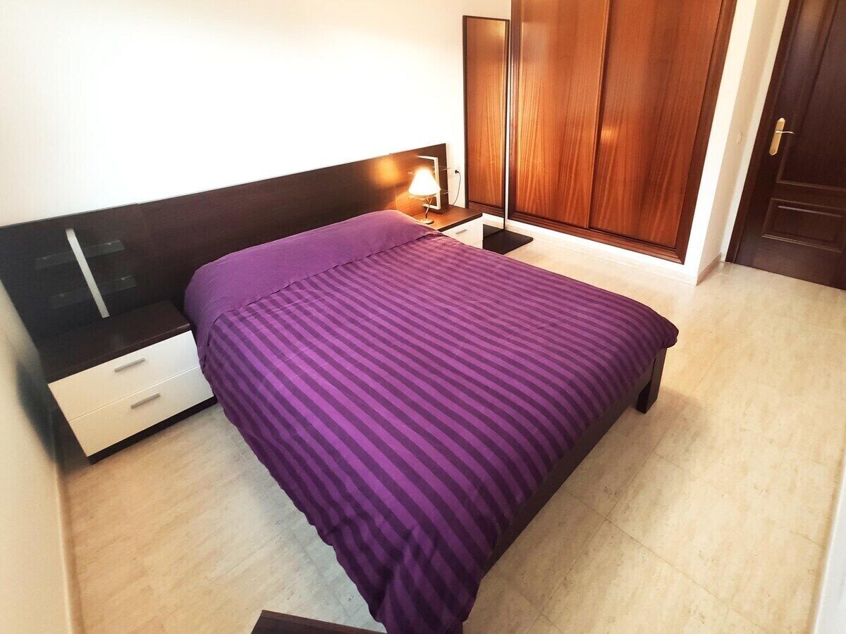 Una camera da letto con un letto, un comodino, una lampada e un armadio.