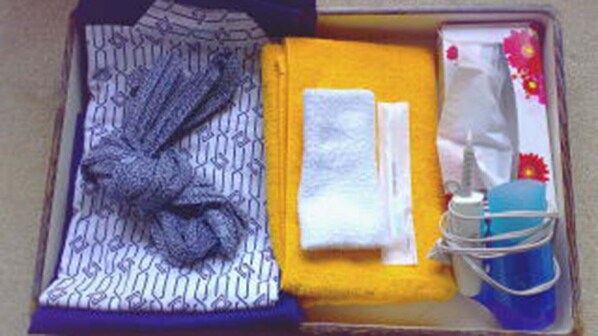 A neatly arranged travel case with a folded garment, a folded towel, a small toiletry bag, and a pair of earphones. - Ryokan Suigou (Yurihama)