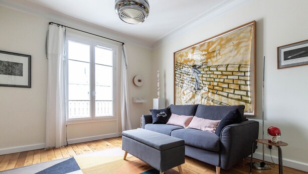 A modern living room with a grey sofa, a patterned rug, and a large abstract painting. - Colour in Ternes, by Veeve (Paris)