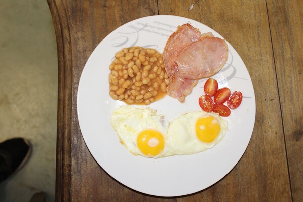 A plate with beans, ham, tomatoes, and eggs.