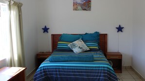 A bedroom with a bed, two bedside tables, a nightstand, a window with curtains, and a wall-mounted star decoration. - African Violet (Mbabane)