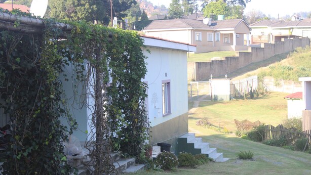 A residential area with houses, a grassy yard, and a staircase leading to a house.