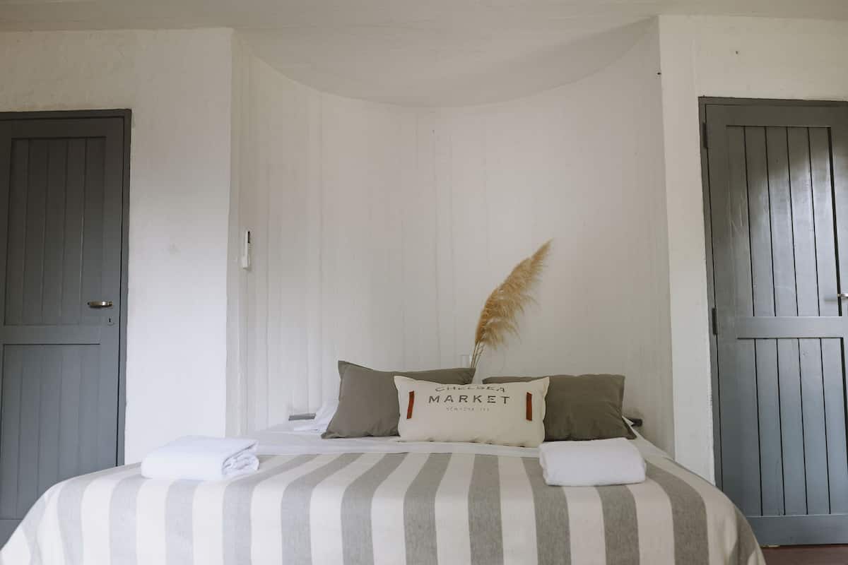 Ein Schlafzimmer mit einem Bett, Kissen, einem Nachttisch und einer Tür.