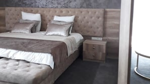 Une chambre à coucher moderne avec un grand lit, une table de chevet et un mur décoré d’un motif imitant le marbre.