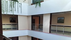 Un atrium à plusieurs niveaux, doté de rampes en verre, de plantes d’intérieur et d’œuvres d’art exposées sur les murs.