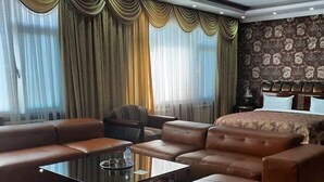 Une chambre d’hôtel comprenant un grand canapé, une table basse et un lit recouvert d’une couvre-lit à motifs.