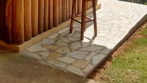 A wooden bar with a stone-tiled patio, a single wooden stool, and a view of the forest through a window. - LEASE, EVENTS, TIROLESA, ARVORISMO, CRAFTSMAN, 360 ° VIEWPOINT (Guaratinguetá)