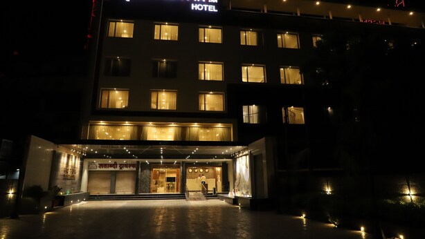 A hotel with a sign reading "RE: GEN: TA INN HOTEL" and a visible entrance with a covered area and steps leading up to it.