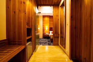 Un pasillo de madera que conduce a una habitación con una cama, un escritorio y una lámpara.