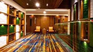 A hotel lobby with a wooden ceiling, green wall panels, and a colorful striped carpet.