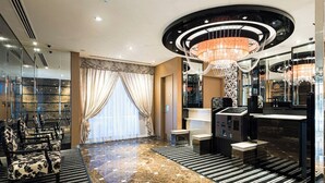 A hotel lobby with a marble floor, a chandelier, seating area, and a reception desk.