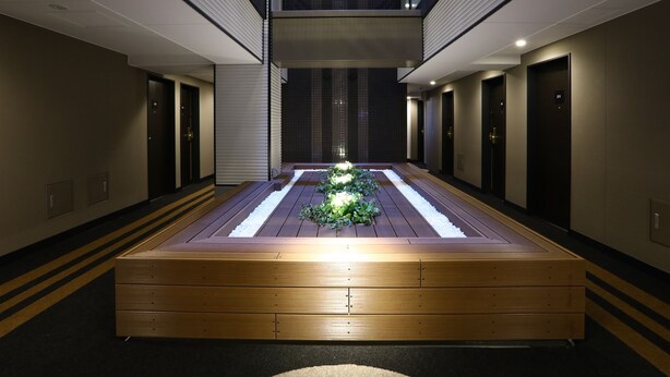 A hotel corridor with wooden flooring, a central lighted pathway, and doors on both sides.