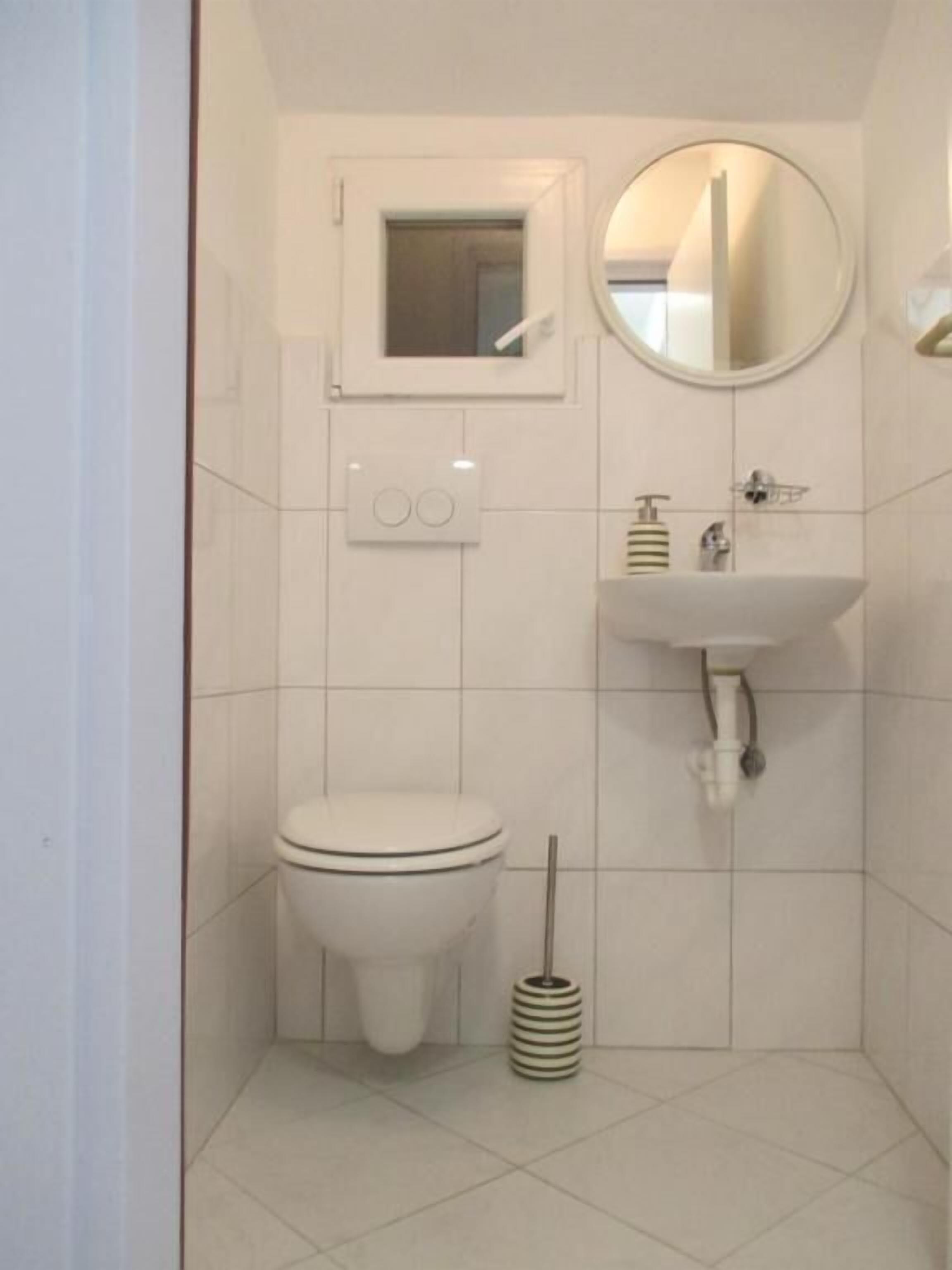 A small, clean bathroom with a toilet, sink, and mirror.