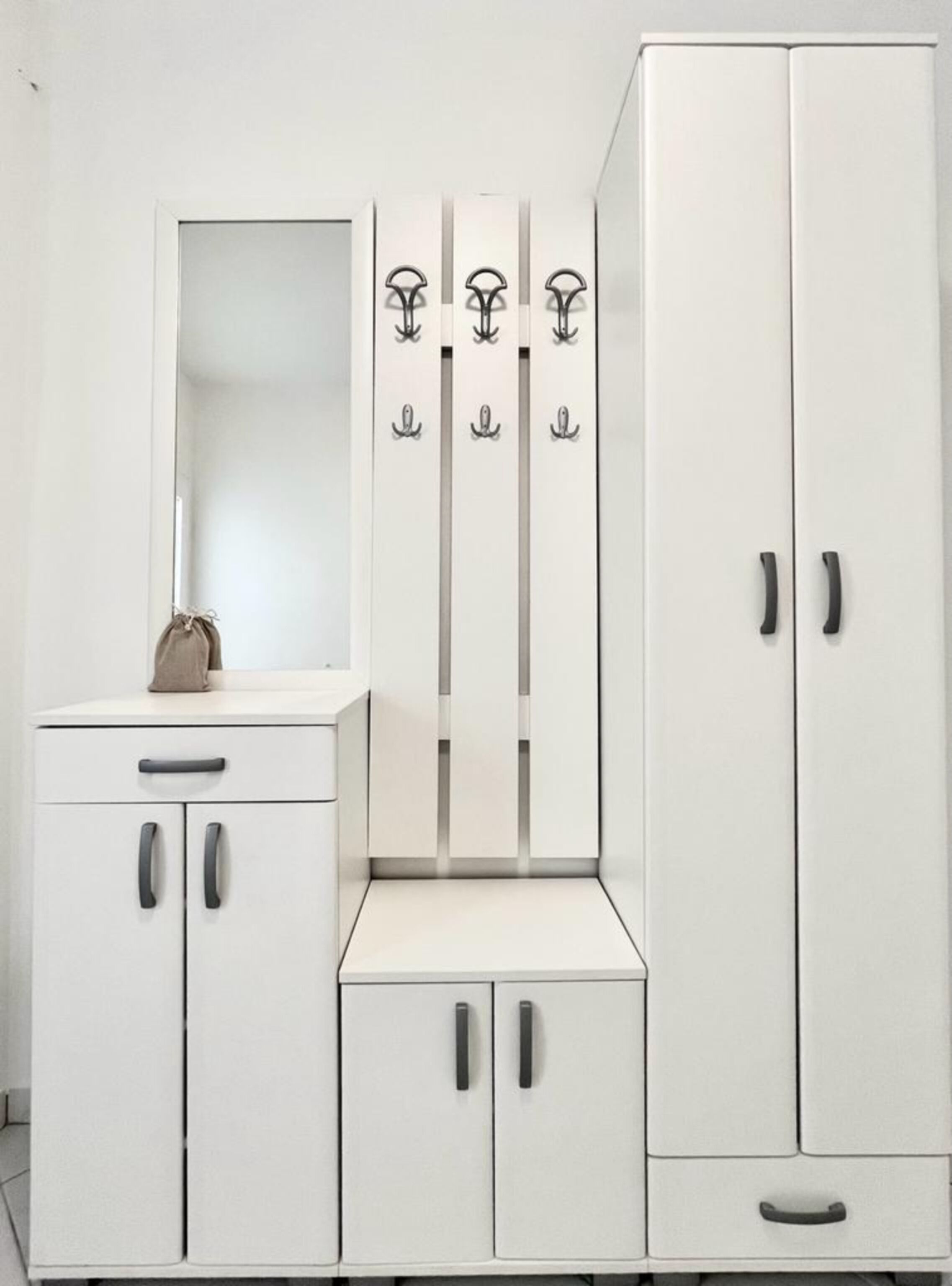 Une armoire blanche à deux portes, dotée d’un miroir et d’un porte-manteau avec des crochets.