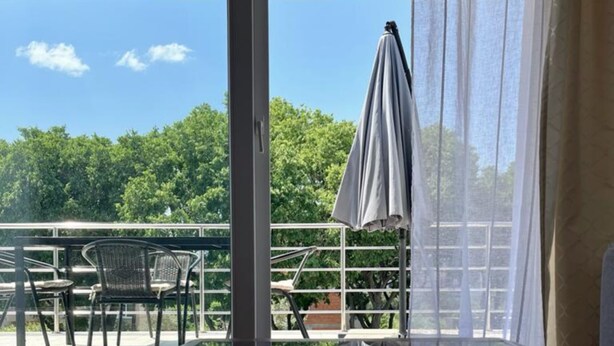 A glass table reflecting a balcony with outdoor furniture and a view of trees and sky. - Lemon Tree Apartments (Zadar)