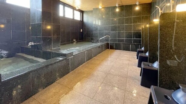 Een moderne spa met een ruime jacuzzi, een aparte douche en een zithoek met een bank.